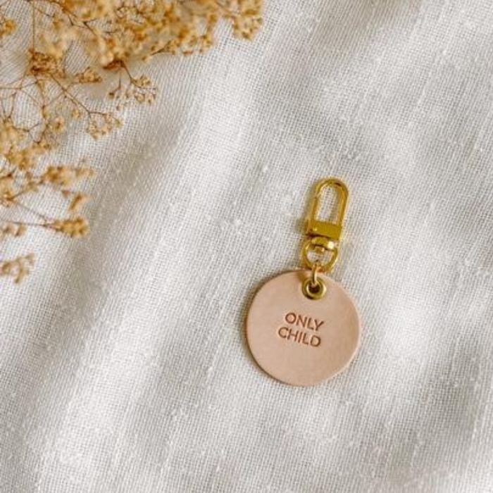 Vegetable tanned leather keychain with brass hardware that says "Only Child"