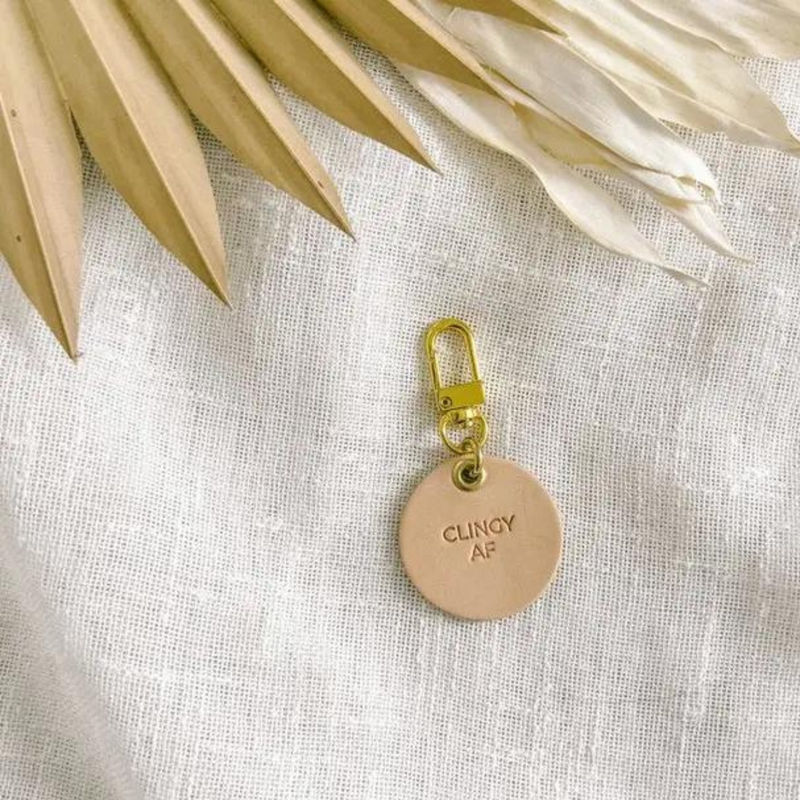 Vegetable tanned leather dog tag with brass hardware that says "Clingy AF"