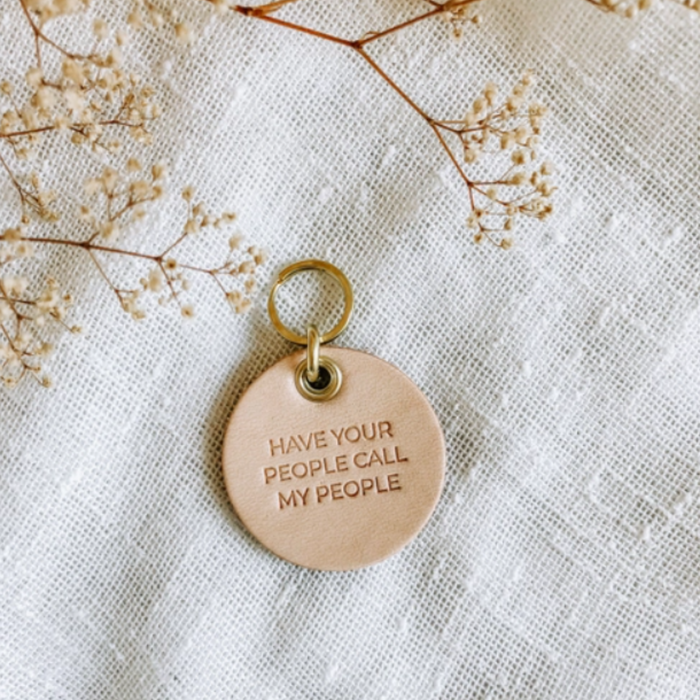 Vegetable tanned leather dog tag with brass hardware that says "Have Your People Call My People"