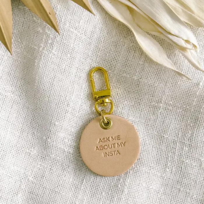 Vegetable tanned leather dog tag with brass hardware that says "Ask Me About My Insta"